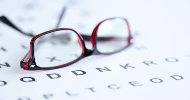 Черно-красные очки для зрения лежат на офтальмологическом столе 4К фильма — стоковое видео
