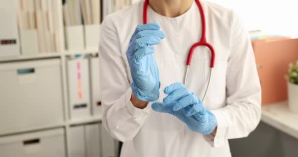 Врач кладет одноразовую перчатку на руки в медицинский кабинет 4К фильм — стоковое видео