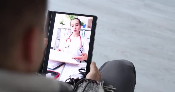 Paciente enfermo que se comunica con el médico a través de un enlace de vídeo utilizando la tableta digital en casa película 4k — Vídeo de stock