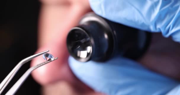 Gloved technician holds magnifying glass and tweezers and looks at gem 4k movie — Stock Video