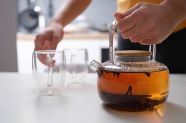 Elleri cam bir çaydanlık ve boş bir bardak, yakın plan.