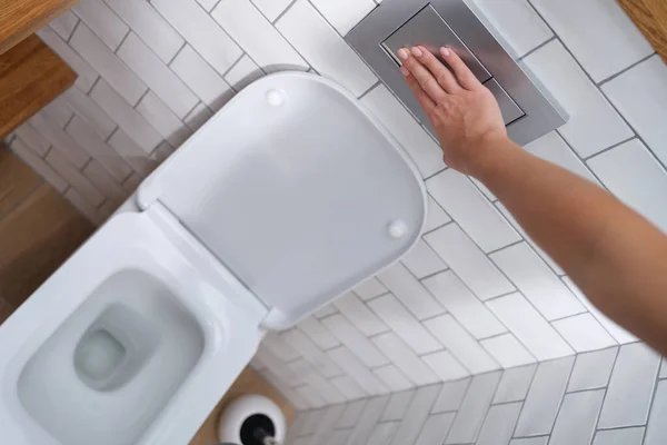 Egy kéz megnyomja a WC-csészét öblítés, közelkép — Stock Fotó