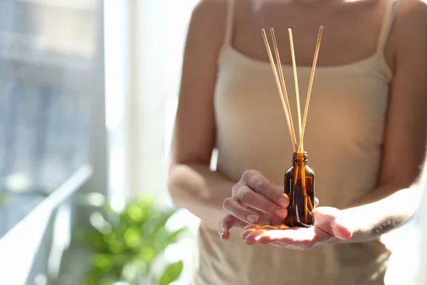 Woman holding diffuser with wooden sticks for aroma oil — Stock Photo, Image