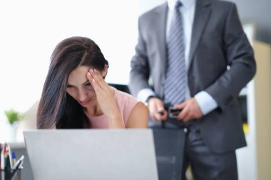 Korkmuş kadın arka planda bilgisayarın başında oturuyor iş adamı kemerini çözüyor.