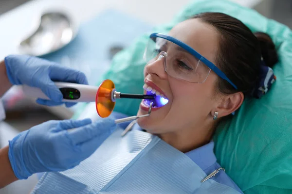 Dentysta posiada lampę LED i przyrząd dentystyczny w ustach pacjenta — Zdjęcie stockowe