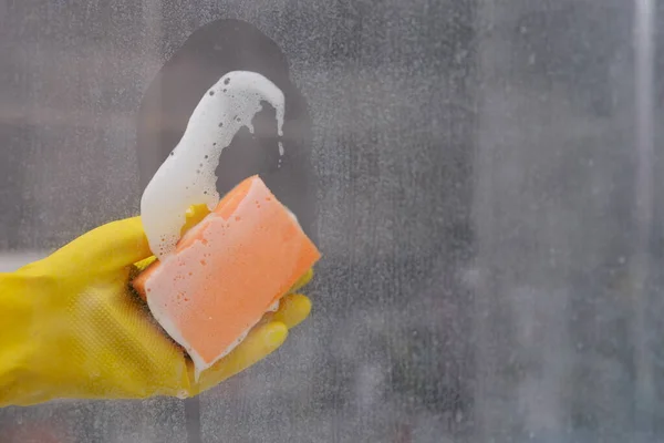 Ręka myje brudne okno gąbką. — Zdjęcie stockowe