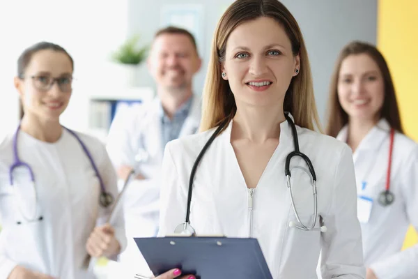 Porträtt av framgångsrik kvinnlig läkare på bakgrund av kollegor — Stockfoto