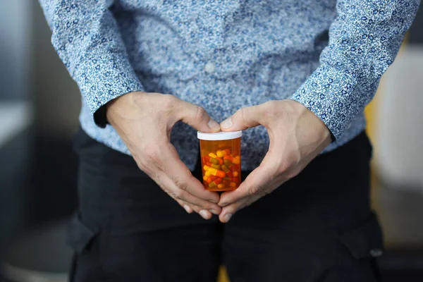 Man holding jar of capsules near genitals closeup — Stock Photo, Image