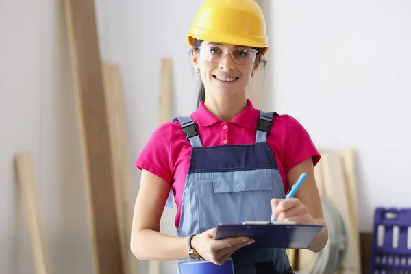 戴防护头盔、手持带有文件的剪贴板的女建筑工人 — 图库照片