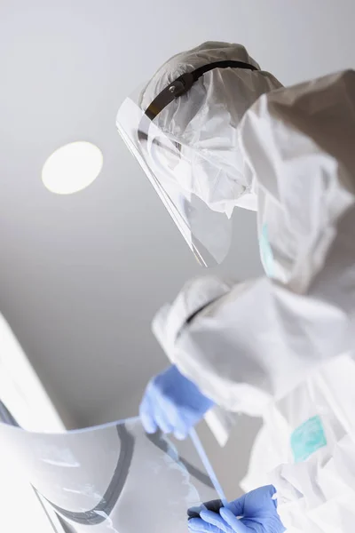 Koruyucu antiveba giysileri ve yüzündeki ekranlar klinikteki röntgene bakıyor. — Stok fotoğraf