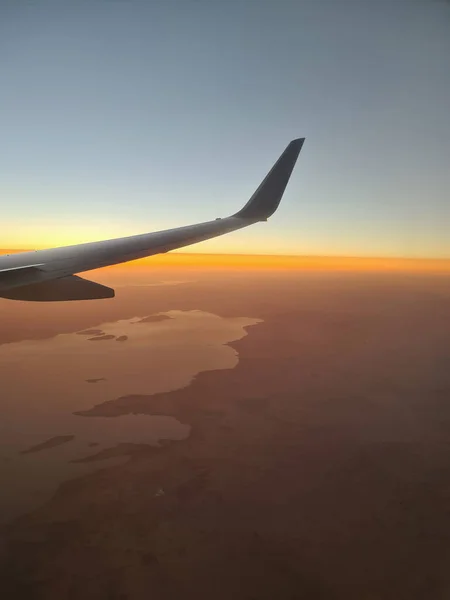Крупный план крыла самолета над землей на фоне заката — стоковое фото