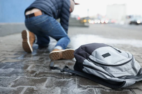 Ryggsäck ligger på hala stenplattor nära fallande man närbild — Stockfoto