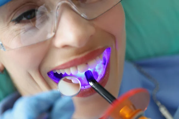 Νεαρή γυναίκα που αντιμετωπίζει τα δόντια με ασύρματη LED θεραπεία φως μηχανή closeup — Φωτογραφία Αρχείου