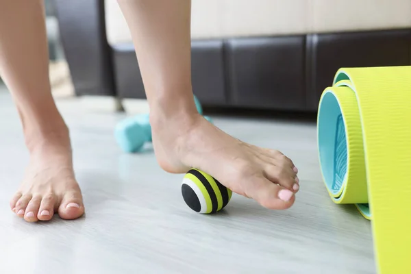 Gambe femminili rotolare piccola palla sportiva sul pavimento a casa primo piano — Foto Stock