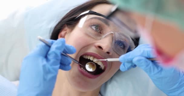 Врач-стоматолог проводит медицинское обследование ротовой полости пациента 4К фильм — стоковое видео