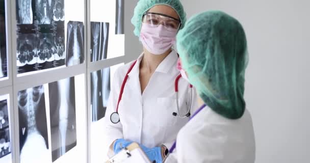의사들은 고글을 쓰고 얼굴을 보호하는 마스크를 착용하고 클리닉 4k 영화에서 엑스레이를 보고 있습니다. — 비디오