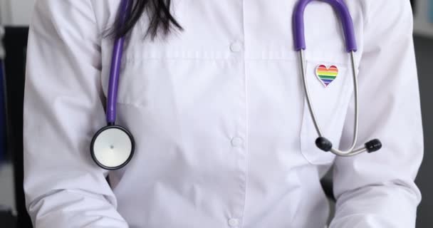 Silueta de médico en bata blanca con estetoscopio e insignia LGBT en la película de bolsillo 4k — Vídeo de stock