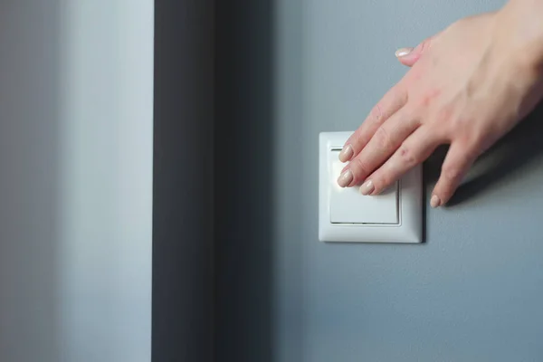 Mão feminina pressionando interruptor de luz no apartamento closeup — Fotografia de Stock
