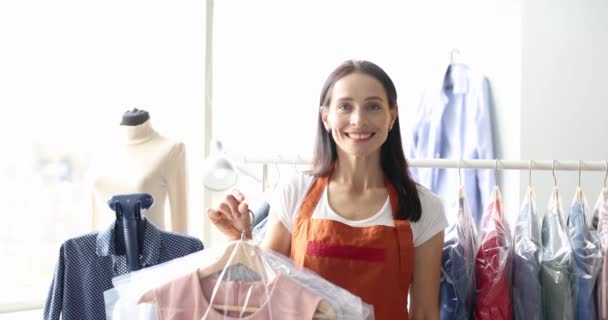Wanita tersenyum memegang pakaian di kantong plastik di tangan di laundry 4k film — Stok Video