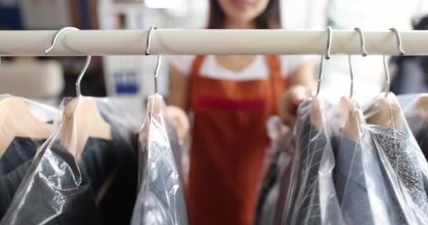Kobieta sortuje ubrania w torbach celofanowych na wieszakach w pralni chemicznej film 4k — Wideo stockowe