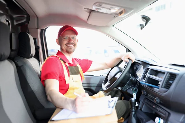 Unrasierter männlicher Kurier sitzt lächelnd im Auto — Stockfoto