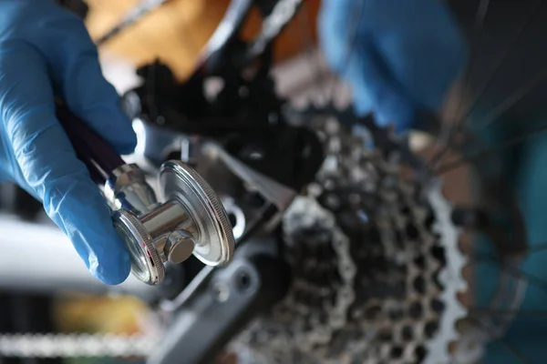 Uma mão de luva segura uma chave para ajustar a bicicleta — Fotografia de Stock