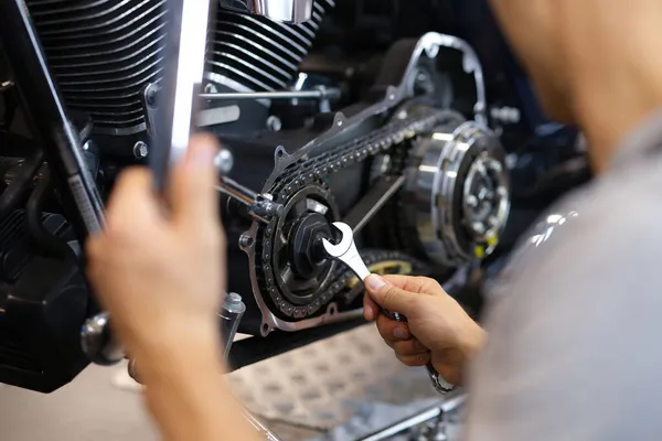 Un uomo gira una parte su una moto con una chiave inglese — Foto Stock