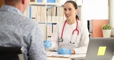 Kadın doktor, resepsiyon 4K filminde erkek hastayla iletişim kuruyor.