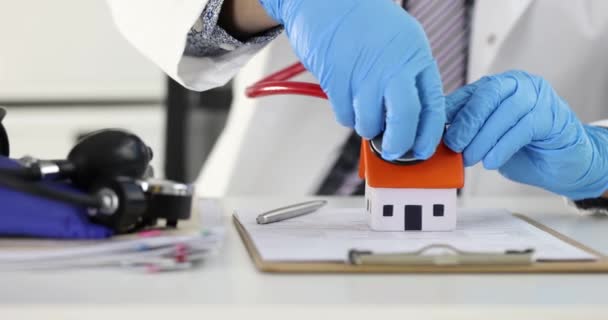 Γιατρός βάζει στηθοσκόπιο στην οροφή του μικρού σπιτιού 4k ταινία — Αρχείο Βίντεο