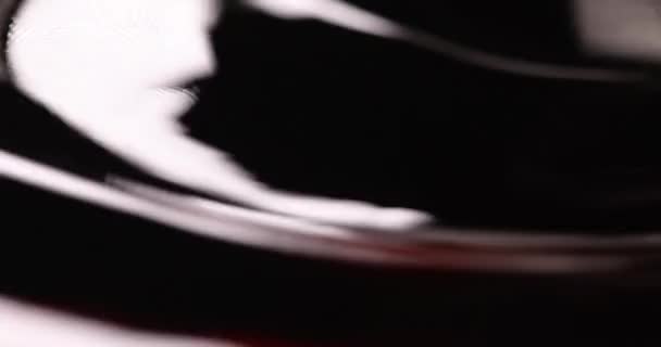 Líquido aceitoso oscuro con tinte rojo en la película de ondas 4k — Vídeos de Stock