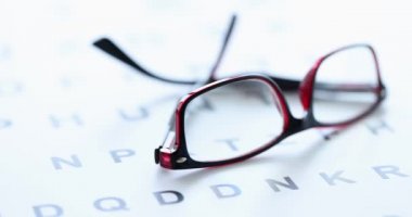 Plastik çerçeveli gözlük, görüş ölçüm masası 4K filminde yatıyor.