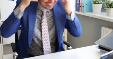 Kulaklıklı genç adam dizüstü bilgisayara bakıyor ve 4K numaralı ofiste dans etmeye başlıyor.