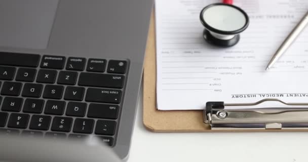 Medical history of patient with ballpoint pen and stethoscope lying on table near laptop 4k movie — Stock Video