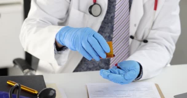 Doctor sitting at table and pouring many capsules from jar into hand 4k movie — Stock Video