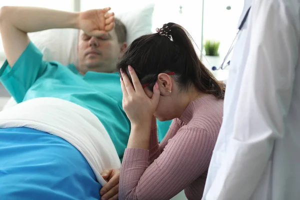 Chica llorando cerca de hombre acostado en la cama en la clínica — Foto de Stock