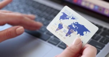 Kadının elinde kredi kartı var ve verileri dizüstü bilgisayarda 4K filme aktarıyor.
