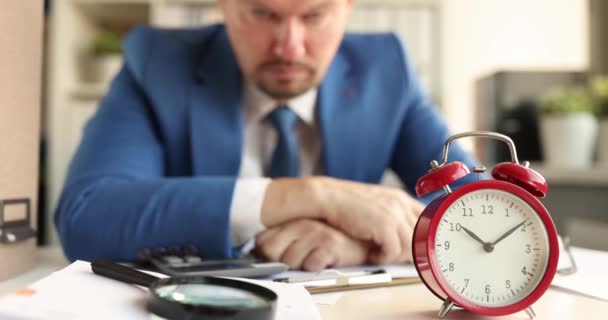 Cansado hombre de negocios se encuentra en el lugar de trabajo cerca de reloj despertador cámara lenta película 4k — Vídeo de stock