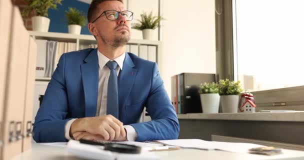 Mladý zamyšlený podnikatel v brýlích sedí na pracovišti zpomalený film 4k — Stock video