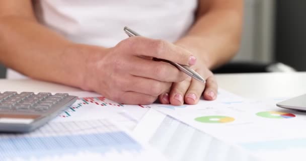 Руки женщины держат ручку на столе с документами бизнес-графики с финансовыми показателями замедленной съемки 4k фильма — стоковое видео