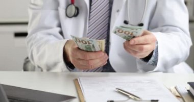 Erkek doktor masada oturuyor ve $4K film yavaş çekim sayıyor.