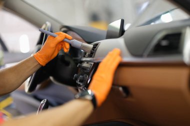 Bir adam arabanın içinde tozu fırçalıyor, elleri yakın.