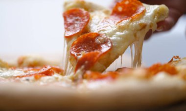 El büyük bir dilim sıcak pizza alır, yakın plan.
