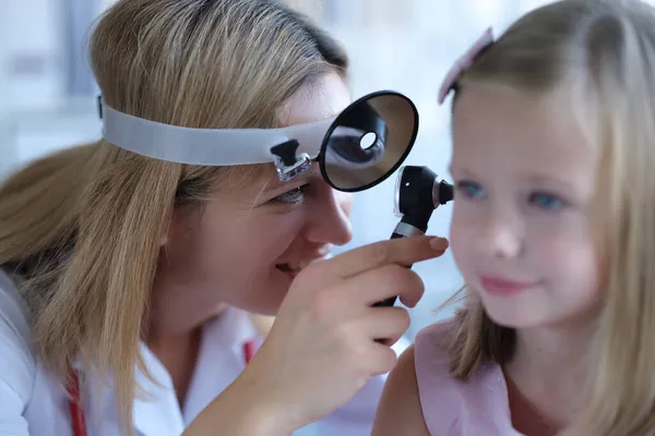 Жінка-педіатр дивиться на вухо маленької дівчинки — стокове фото