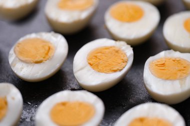 Haşlanmış tavuk yumurtaları koyu arkaplanda ikiye bölünmüş.