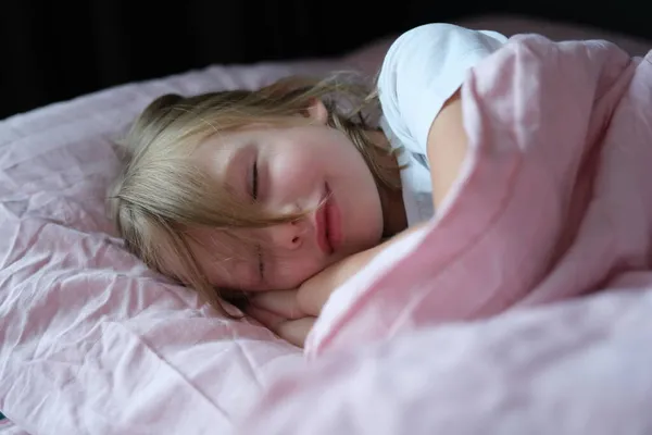 Lille pige sover fredeligt på sengen - Stock-foto