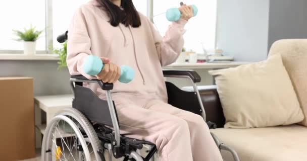 Mujer joven haciendo ejercicios de mano mientras está sentado en silla de ruedas de movimiento bajo 4k película — Vídeo de stock