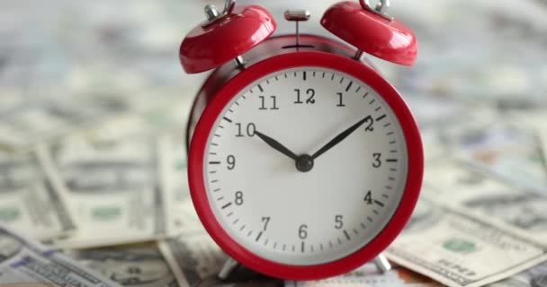 Red alarm clock for ten in morning stands on one hundred dollar bills slow motion 4k movie — Stock Video