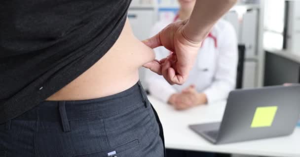 Paciente masculino mostrando pliegue de grasa en el abdomen en la cita con el médico primer plano película 4k cámara lenta — Vídeos de Stock