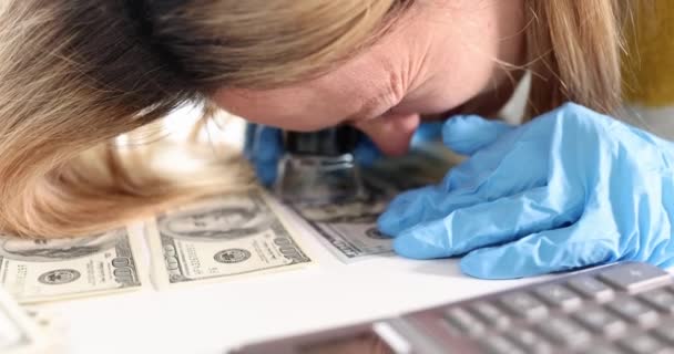 Γυναίκα εμπειρογνώμονας κοιτάζοντας τα χρήματα μέσα από μεγεθυντικό φακό 4k ταινία αργή κίνηση — Αρχείο Βίντεο