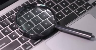 Laptop klavyesinde duran büyüteç. Yakın çekim 4K film ağır çekim.